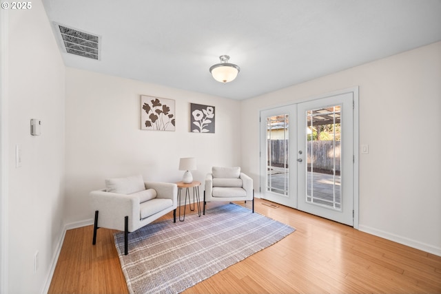 living area with hardwood / wood-style flooring and french doors