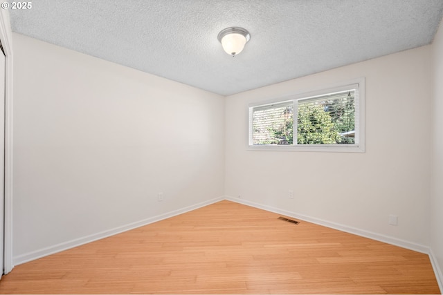 empty room with hardwood / wood-style flooring and a textured ceiling