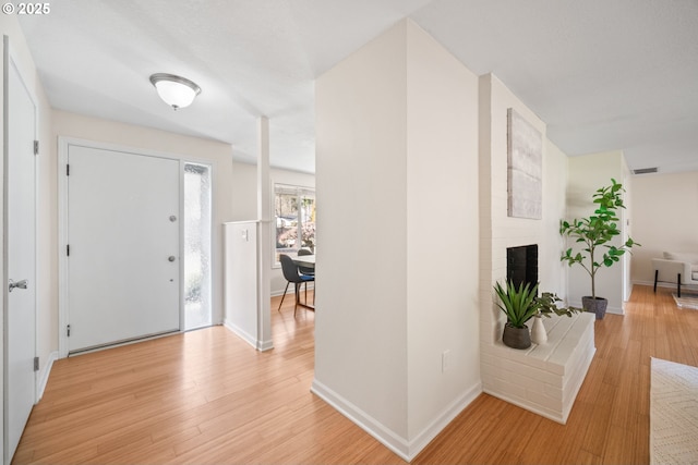 foyer with a fireplace and light hardwood / wood-style floors