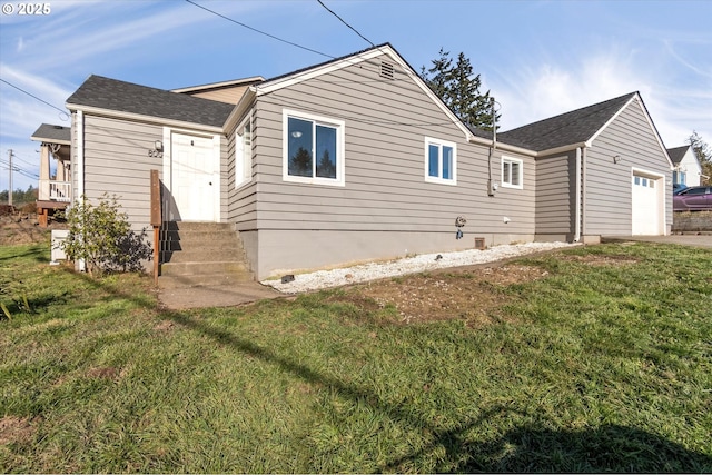 rear view of property with a garage and a lawn