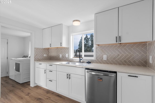 kitchen with washer / dryer, sink, white cabinetry, stainless steel dishwasher, and backsplash