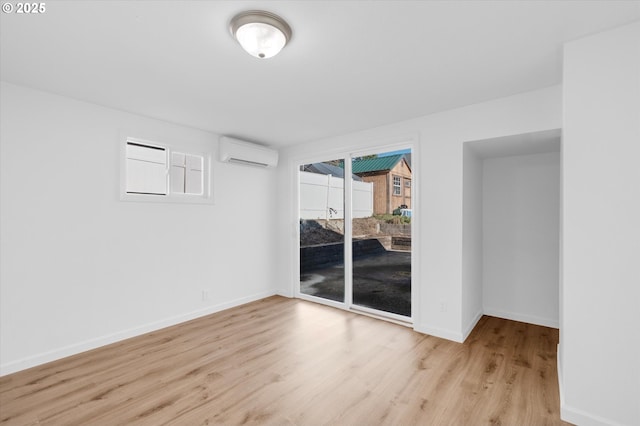 empty room featuring a wall mounted AC and light wood-type flooring