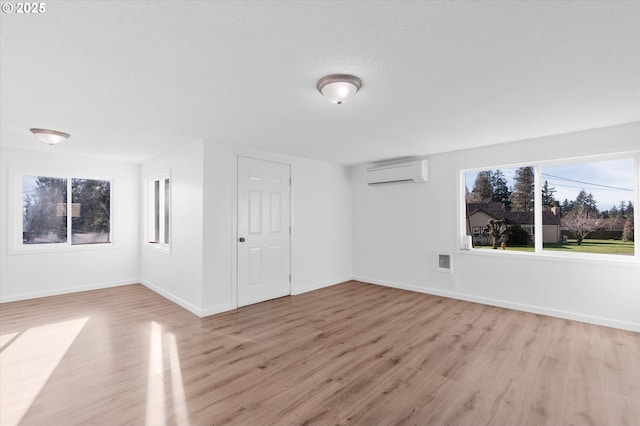 unfurnished room featuring a wall unit AC and light hardwood / wood-style flooring