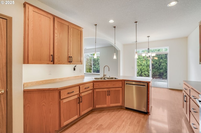 kitchen with light wood-style flooring, a sink, a peninsula, light countertops, and dishwasher