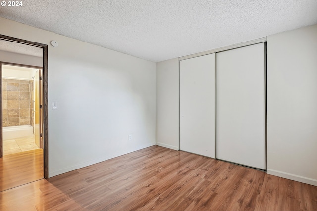 3103/3109 SE 6th Ave, Portland, OR 97202 - unfurnished bedroom featuring a closet, a textured ceiling, baseboards, and wood finished floors