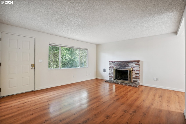 3103/3109 SE 6th Ave, Portland, OR 97202 - unfurnished living room featuring a brick fireplace, a textured ceiling, baseboards, and wood finished floors