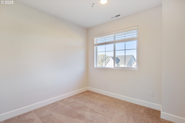 empty room featuring visible vents, light carpet, and baseboards
