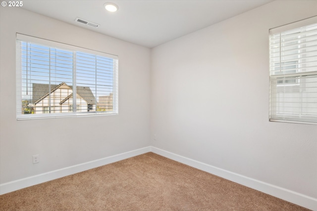 empty room featuring visible vents, baseboards, and carpet