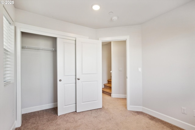 unfurnished bedroom with recessed lighting, a closet, baseboards, and light colored carpet