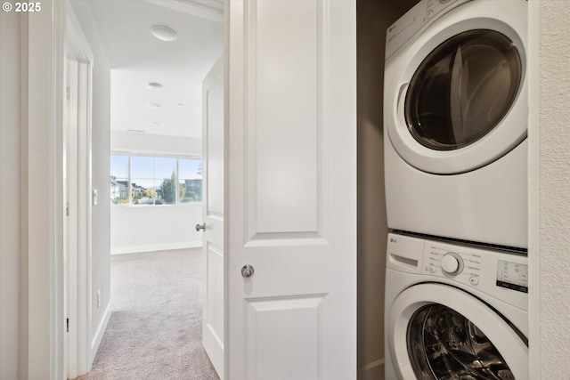 clothes washing area with baseboards, carpet floors, stacked washer and clothes dryer, and laundry area