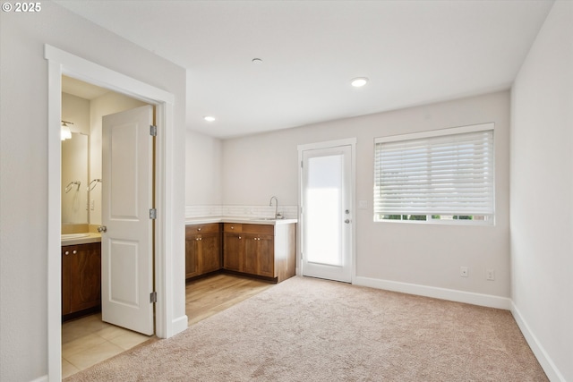 kitchen featuring a sink, light countertops, baseboards, and light carpet