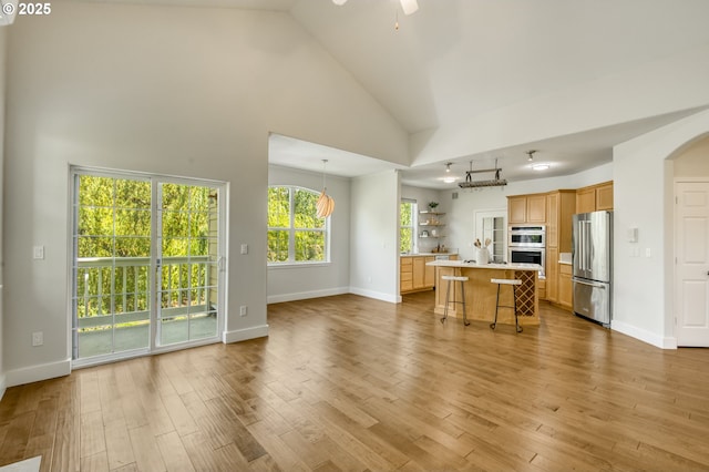 4630 Summerlinn Way W, Linn, OR 97068 - kitchen featuring stainless steel appliances, light countertops, a kitchen bar, open floor plan, and wood finished floors