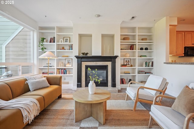 living room with built in features, a high end fireplace, and plenty of natural light