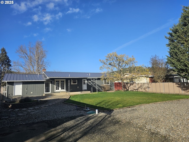 back of house with metal roof, fence, a yard, stairway, and a chimney