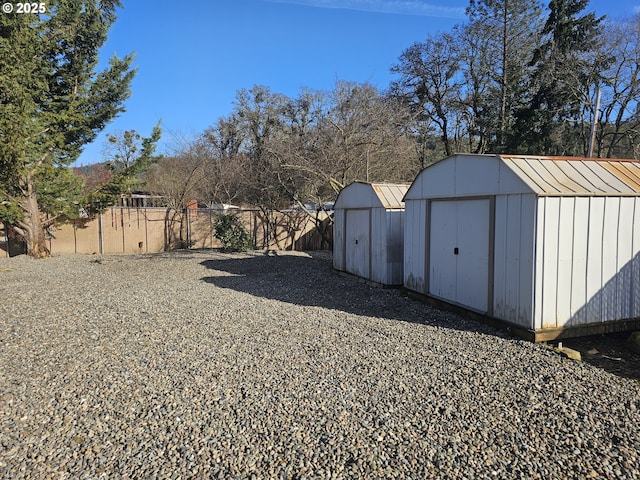 view of yard featuring an outbuilding, a shed, and fence