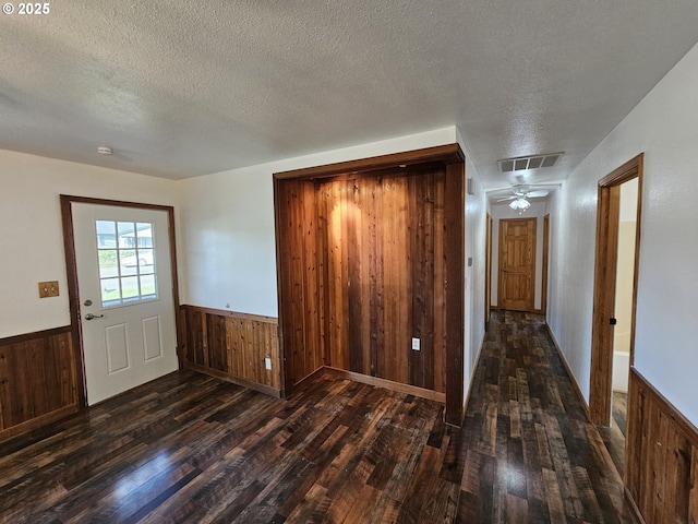 entrance foyer featuring wainscoting, dark wood finished floors, and visible vents