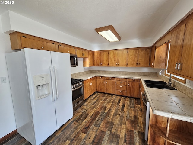 kitchen featuring appliances with stainless steel finishes, dark wood-type flooring, a sink, and brown cabinets