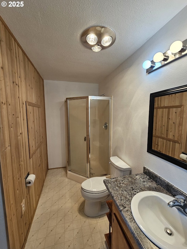 full bathroom with toilet, a textured ceiling, vanity, a shower stall, and tile patterned floors