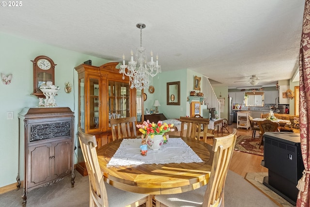 dining space featuring light wood-style floors, a textured ceiling, and ceiling fan with notable chandelier