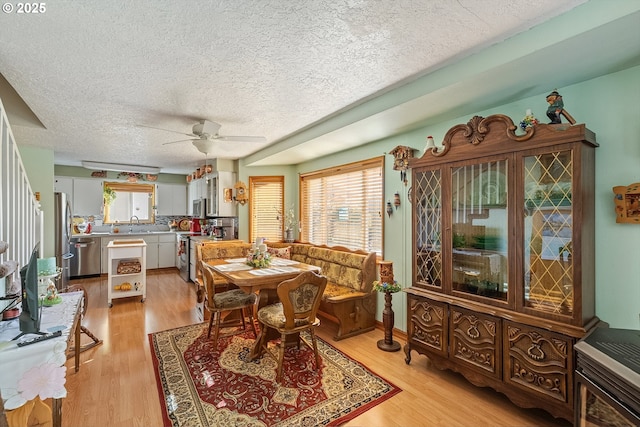 dining room featuring a ceiling fan, a textured ceiling, and light wood-style floors