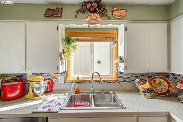 kitchen featuring light countertops, tasteful backsplash, white cabinets, and a sink