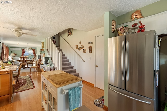 kitchen featuring ceiling fan, a textured ceiling, light wood finished floors, and freestanding refrigerator