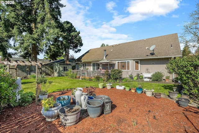 back of house with a yard, a shingled roof, a fenced backyard, and a deck