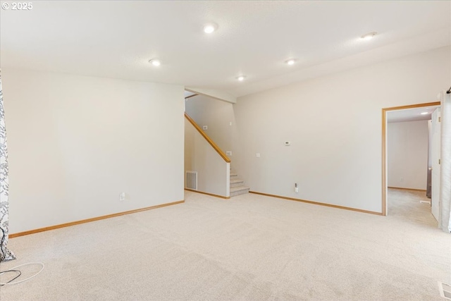 basement featuring visible vents, stairs, baseboards, recessed lighting, and light colored carpet