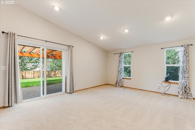 empty room with a wealth of natural light, lofted ceiling, and light colored carpet