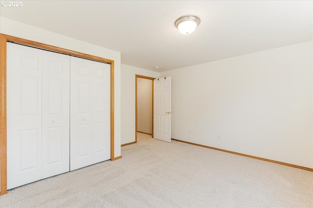 unfurnished bedroom with baseboards, a closet, and light colored carpet