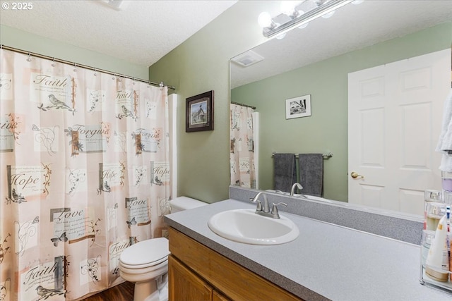 bathroom with vanity, toilet, a textured ceiling, wood finished floors, and visible vents