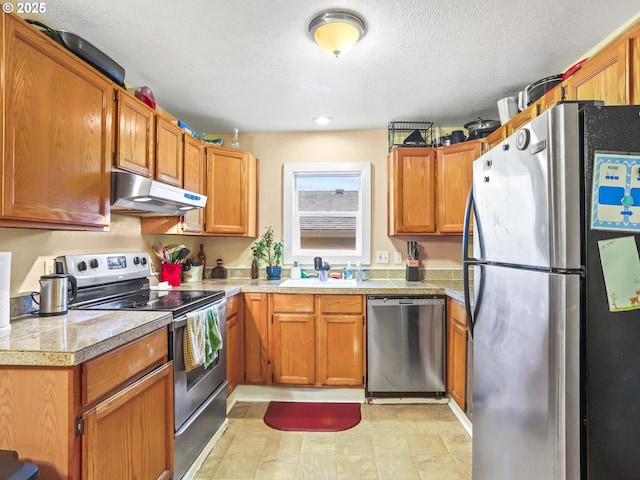 kitchen with appliances with stainless steel finishes, a textured ceiling, and sink