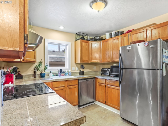 kitchen with a textured ceiling, stainless steel appliances, and sink