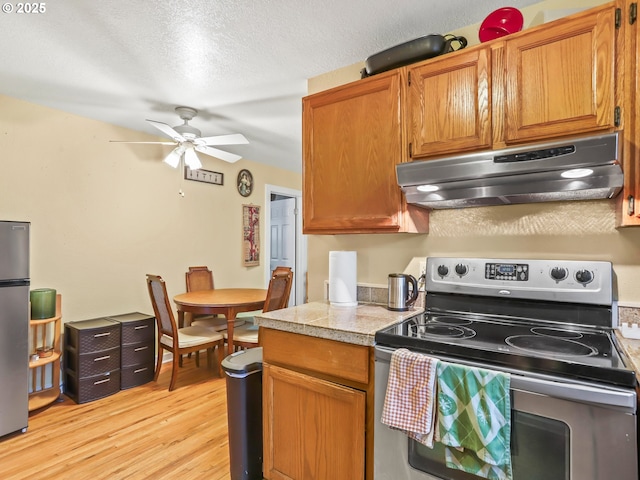 kitchen featuring a textured ceiling, ceiling fan, light hardwood / wood-style floors, and stainless steel appliances