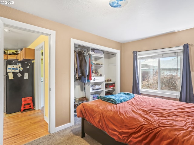 carpeted bedroom featuring refrigerator and a closet