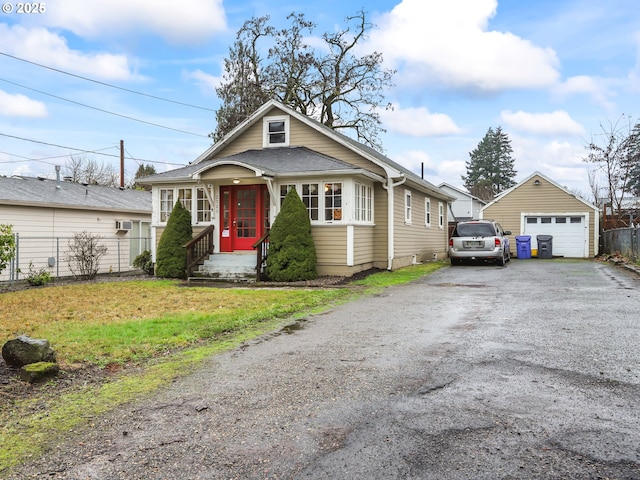 bungalow-style home with a garage, an outbuilding, and a front lawn