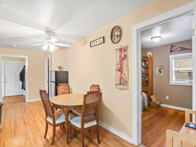 dining space with ceiling fan, light hardwood / wood-style floors, and a textured ceiling