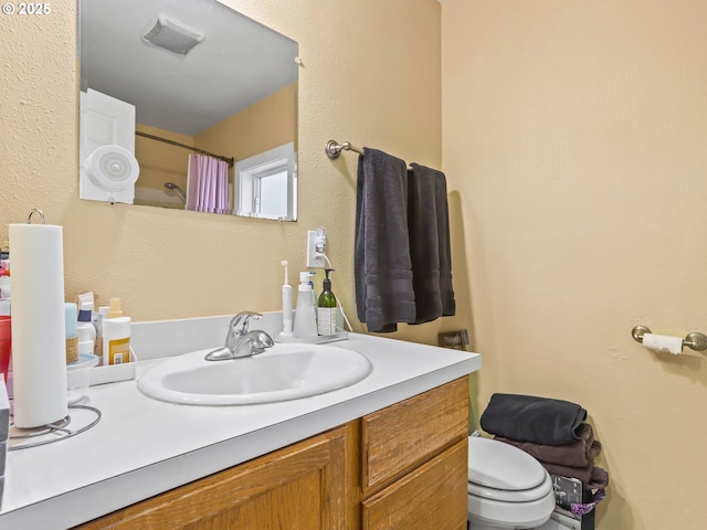 bathroom featuring vanity, curtained shower, and toilet