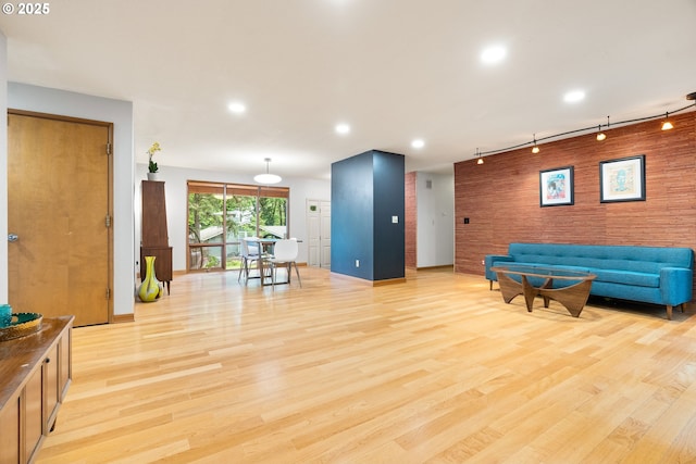 workout area with wooden walls, baseboards, track lighting, and light wood-type flooring