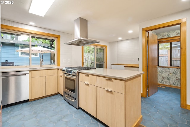 kitchen featuring a peninsula, light brown cabinets, extractor fan, a sink, and appliances with stainless steel finishes