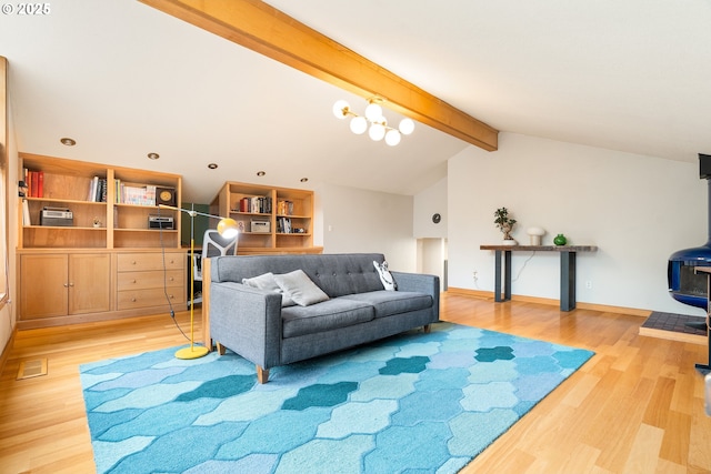 living room featuring lofted ceiling with beams, a wood stove, baseboards, wood finished floors, and visible vents