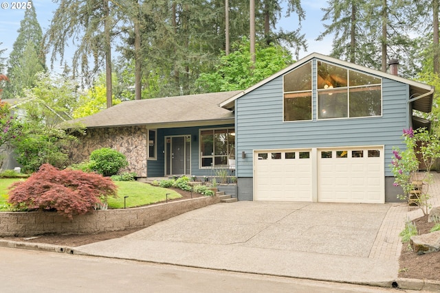 split level home with covered porch, an attached garage, driveway, and stone siding