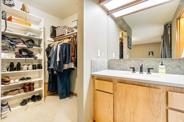 bathroom featuring vanity, decorative backsplash, and a spacious closet