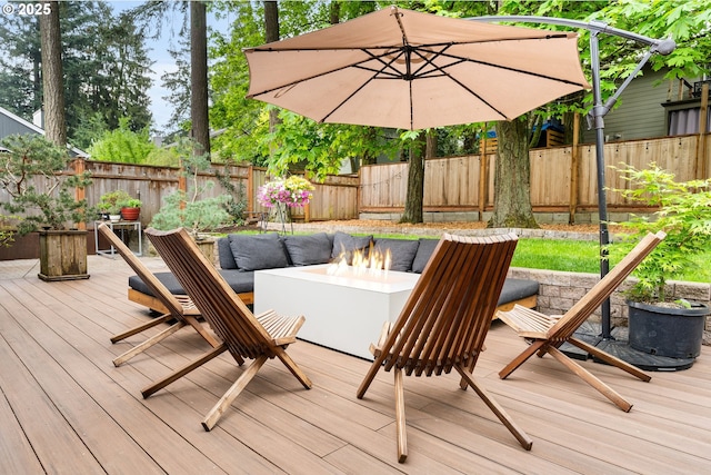 wooden terrace with a fenced backyard and an outdoor living space with a fire pit
