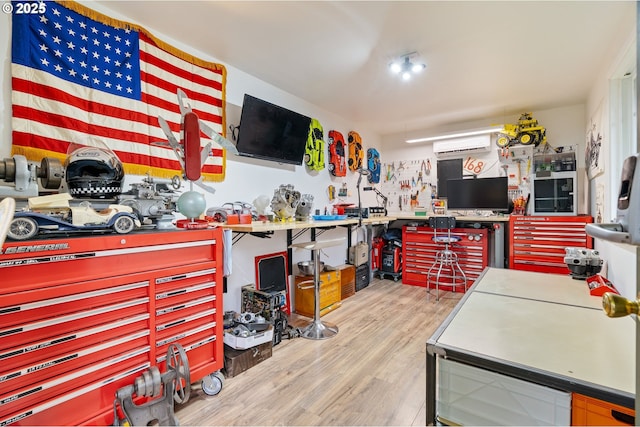interior space featuring a workshop area, a wall unit AC, and wood finished floors