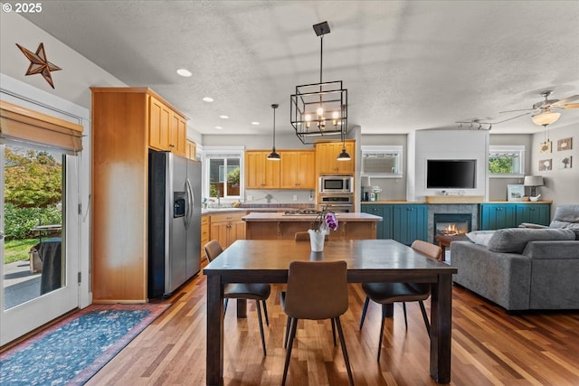 1609 Wood Duck St, Silverton, OR 97381 - dining room featuring wood finished floors, a glass covered fireplace, a textured ceiling, recessed lighting, and ceiling fan