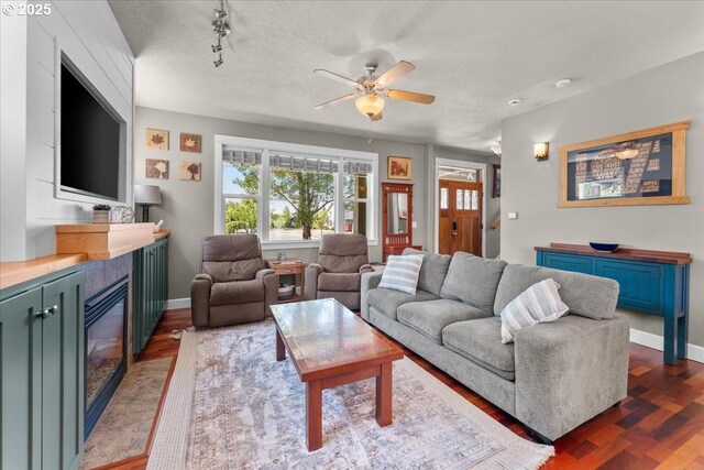 1609 Wood Duck St, Silverton, OR 97381 - living room featuring a glass covered fireplace, a ceiling fan, and dark wood-style flooring