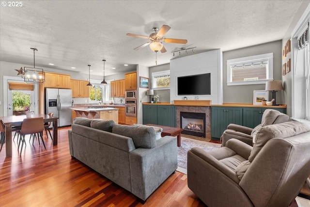 1609 Wood Duck St, Silverton, OR 97381 - living area featuring a ceiling fan, wood finished floors, a glass covered fireplace, a textured ceiling, and recessed lighting