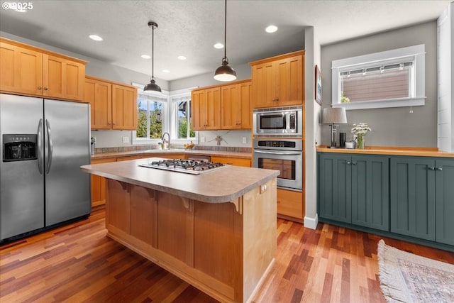 1609 Wood Duck St, Silverton, OR 97381 - kitchen featuring stainless steel appliances, light wood-style floors, a center island, recessed lighting, and a kitchen bar