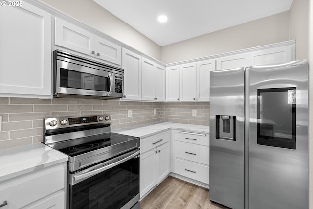 kitchen featuring light wood-style floors, stainless steel appliances, tasteful backsplash, and white cabinetry